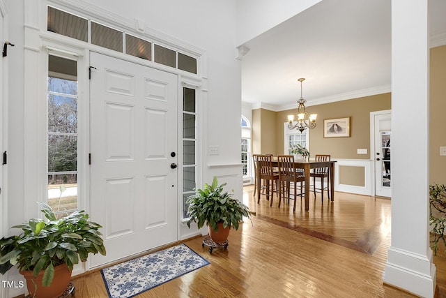 entrance foyer featuring wood-type flooring, crown molding, and a notable chandelier