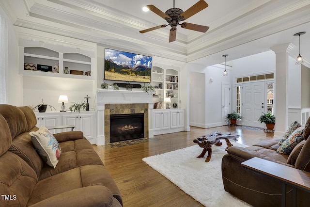 living room featuring built in shelves, ceiling fan, crown molding, and a tiled fireplace