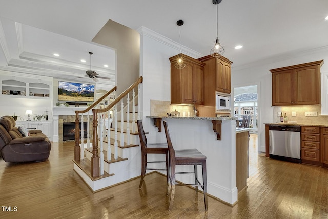 kitchen with ceiling fan, stainless steel dishwasher, decorative light fixtures, a breakfast bar, and white microwave