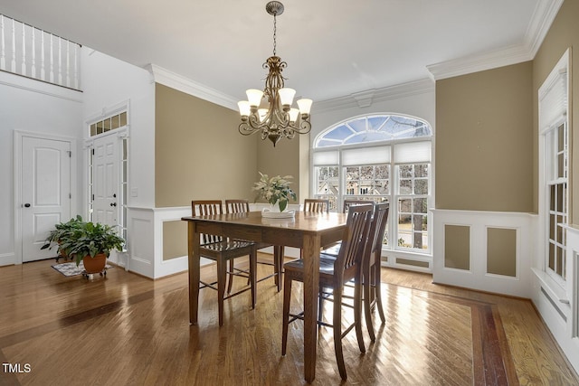 dining room with hardwood / wood-style flooring, an inviting chandelier, and ornamental molding