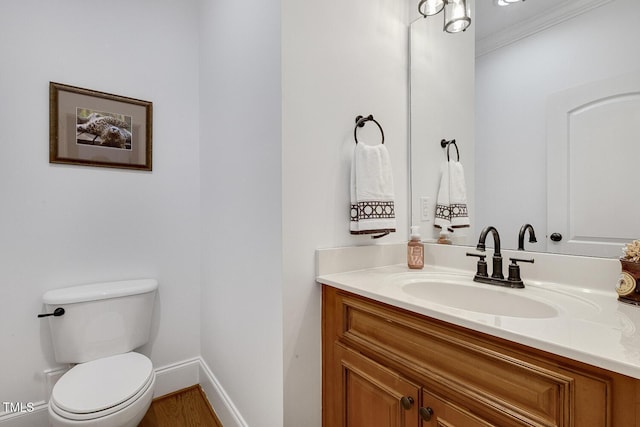 bathroom featuring hardwood / wood-style flooring, vanity, toilet, and crown molding