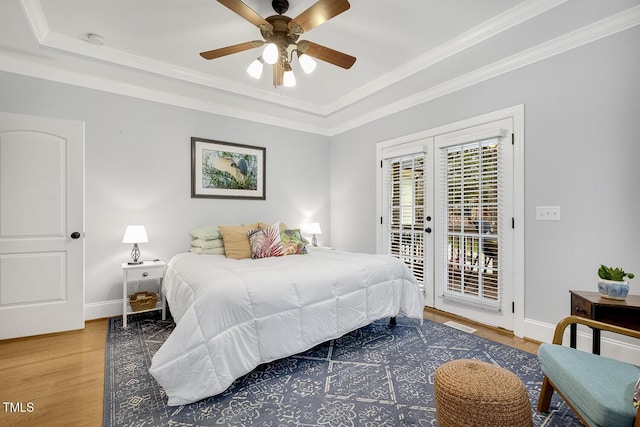 bedroom with hardwood / wood-style flooring, ceiling fan, access to exterior, and a tray ceiling