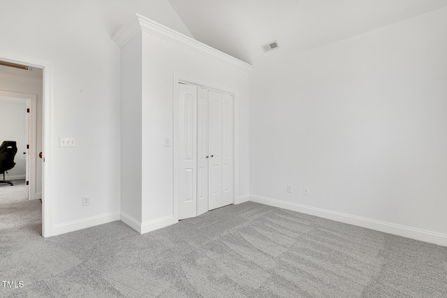 unfurnished bedroom with a closet, light carpet, and vaulted ceiling