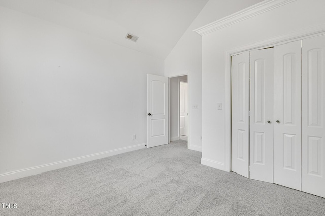 unfurnished bedroom featuring vaulted ceiling, crown molding, light carpet, and a closet