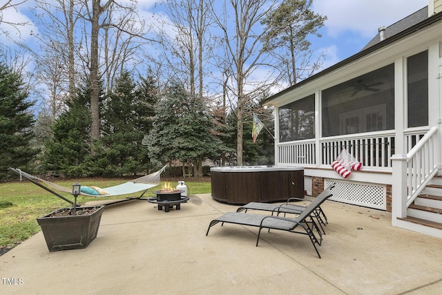 view of patio featuring a sunroom, a hot tub, and an outdoor fire pit