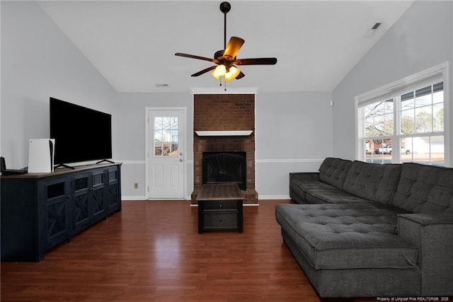 living room with ceiling fan, dark wood-type flooring, lofted ceiling, and a brick fireplace