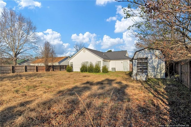 back of property with a lawn, central AC unit, and a shed