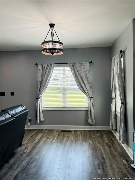 unfurnished dining area with a notable chandelier and dark hardwood / wood-style flooring