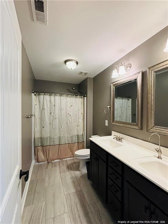 bathroom with walk in shower, vanity, and toilet