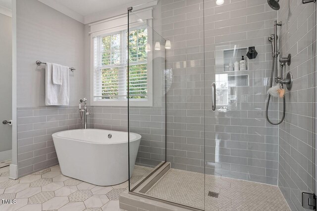 bathroom with tile walls, tile patterned flooring, ornamental molding, and shower with separate bathtub