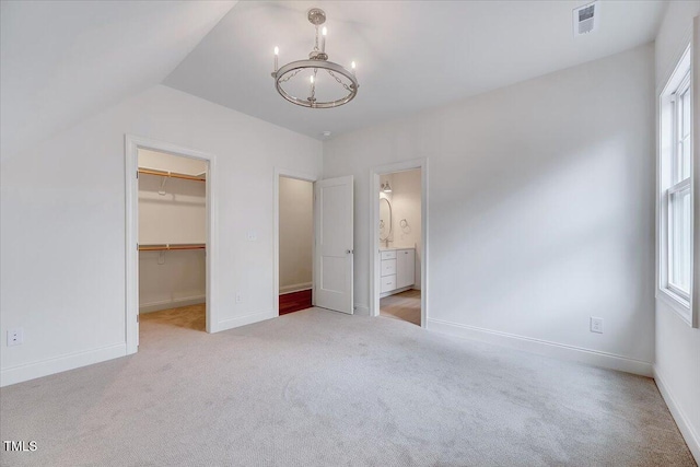 unfurnished bedroom with lofted ceiling, light colored carpet, a walk in closet, and a closet