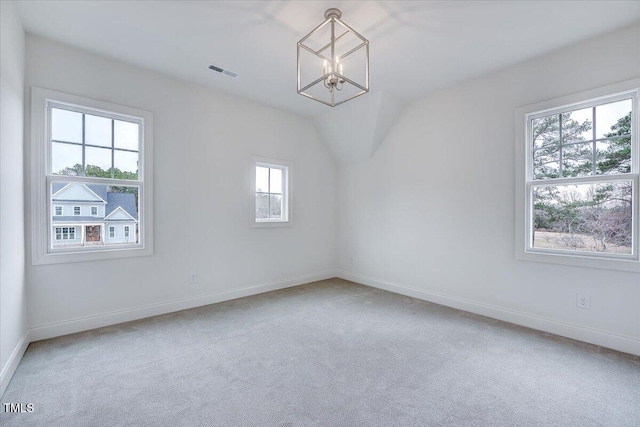 unfurnished room featuring carpet floors, vaulted ceiling, an inviting chandelier, and a healthy amount of sunlight