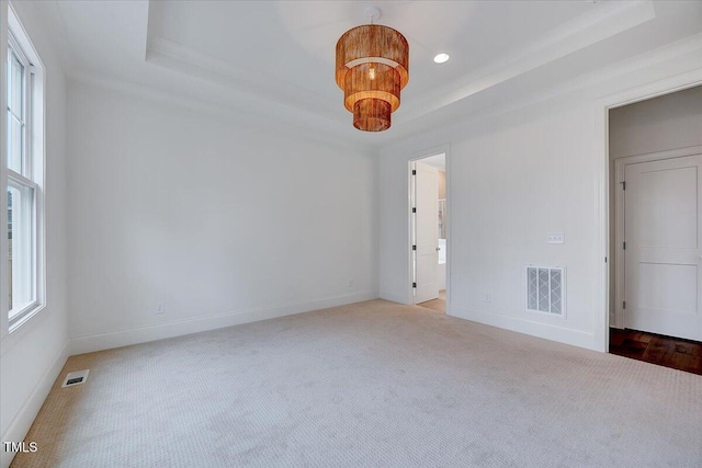 unfurnished bedroom featuring a raised ceiling, carpet flooring, and an inviting chandelier