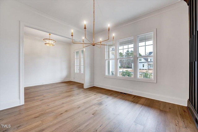 unfurnished dining area with crown molding, hardwood / wood-style floors, and a notable chandelier