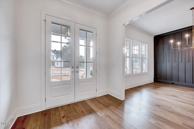 entryway with crown molding, french doors, and light wood-type flooring