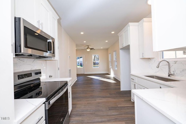 kitchen with light stone countertops, backsplash, stainless steel appliances, sink, and white cabinetry