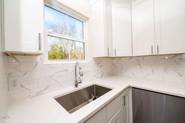 kitchen featuring light stone countertops, white cabinetry, sink, and tasteful backsplash