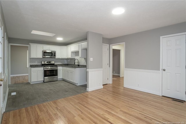 5193 Southport Dr, Fayetteville, NC 28311 - kitchen with white cabinets, sink, tasteful backsplash, light hardwood / wood-style floors, and stainless steel appliances