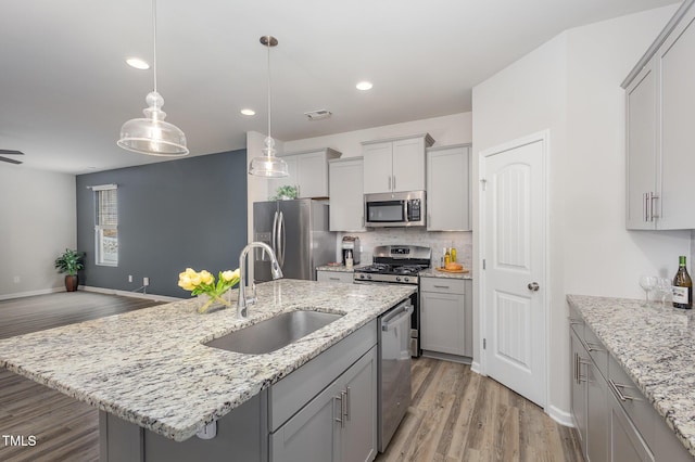 kitchen with gray cabinetry, sink, a kitchen island with sink, and stainless steel appliances