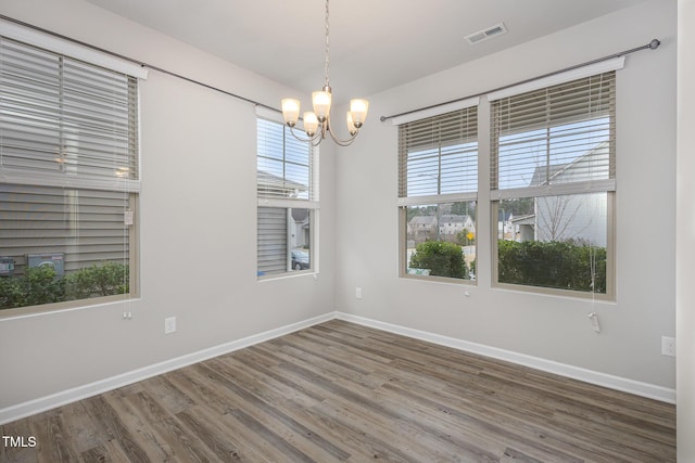 spare room featuring hardwood / wood-style flooring and a notable chandelier