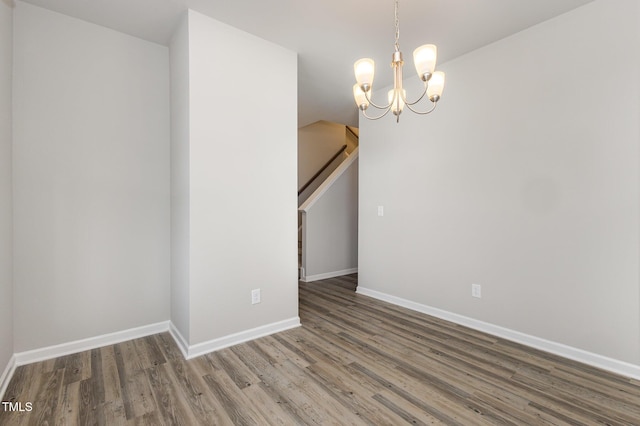 empty room featuring an inviting chandelier and hardwood / wood-style floors