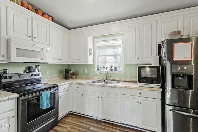 kitchen with sink, dark wood-type flooring, stainless steel appliances, a textured ceiling, and white cabinets