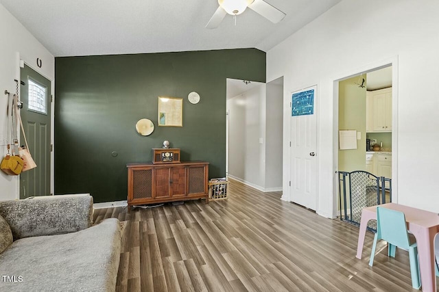 living area featuring ceiling fan, vaulted ceiling, and wood-type flooring