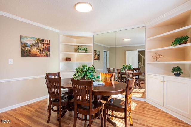 dining room with built in features, crown molding, and light hardwood / wood-style flooring