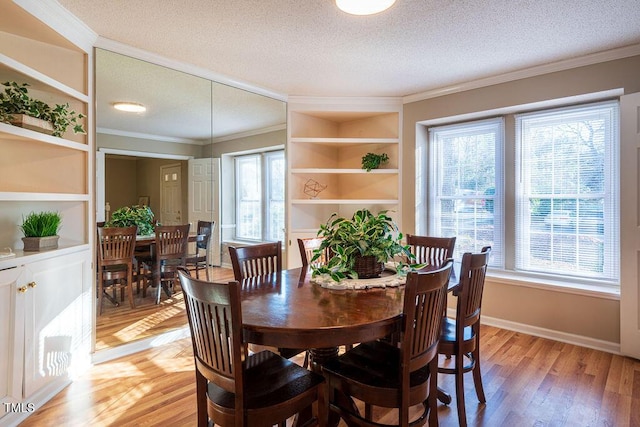 dining space featuring a healthy amount of sunlight, wood-type flooring, a textured ceiling, and ornamental molding