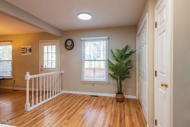 foyer featuring beamed ceiling and light hardwood / wood-style floors