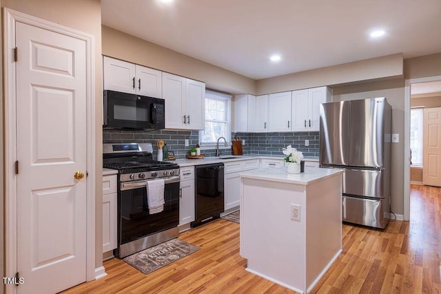 kitchen with sink, a kitchen island, light hardwood / wood-style flooring, white cabinets, and black appliances