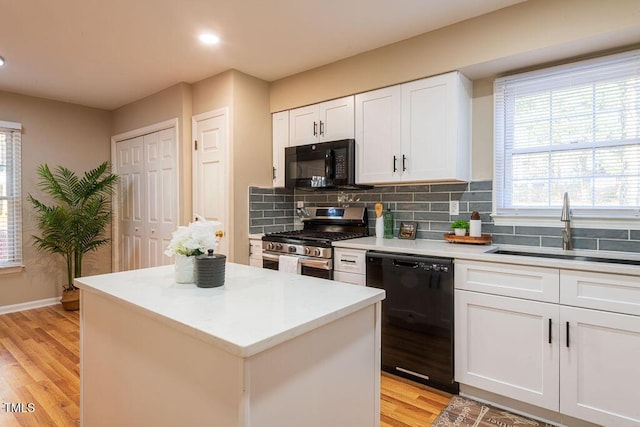 kitchen featuring sink, black appliances, white cabinets, light hardwood / wood-style floors, and a kitchen island