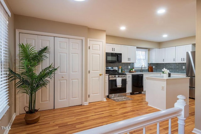 kitchen with tasteful backsplash, sink, black appliances, a center island, and white cabinetry