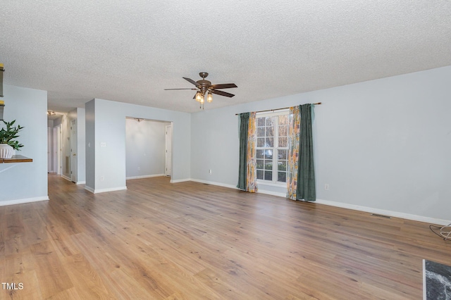 empty room with ceiling fan, light wood-type flooring, and a textured ceiling