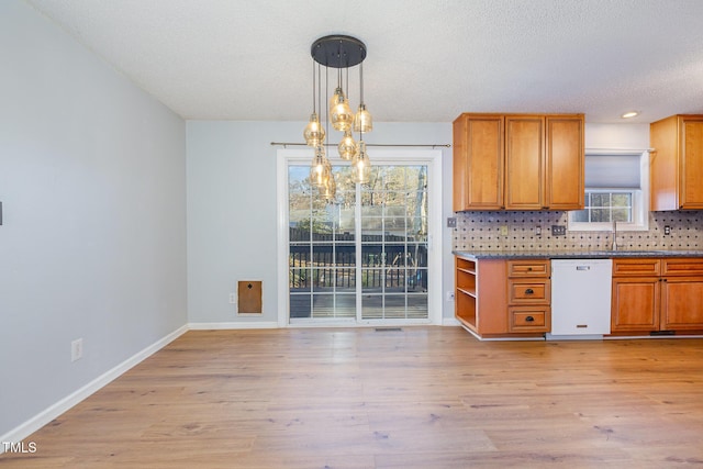 kitchen with white dishwasher, hanging light fixtures, a textured ceiling, and light hardwood / wood-style floors