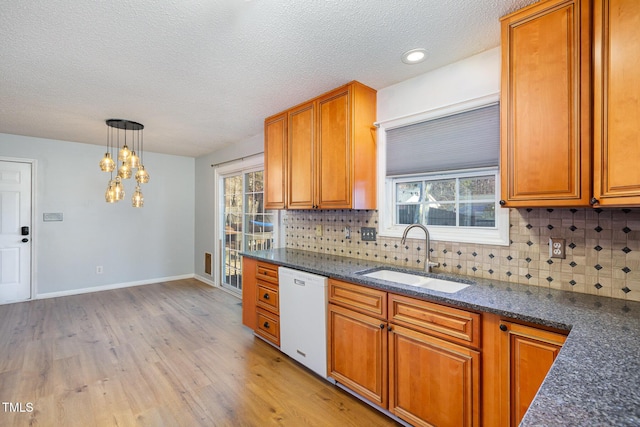 kitchen featuring tasteful backsplash, sink, dishwasher, light hardwood / wood-style floors, and hanging light fixtures