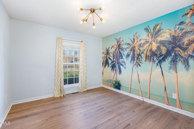 spare room with hardwood / wood-style flooring, a notable chandelier, and a textured ceiling