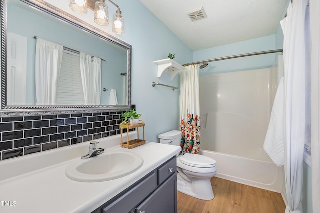 full bathroom featuring backsplash, hardwood / wood-style flooring, toilet, shower / bath combo with shower curtain, and a textured ceiling