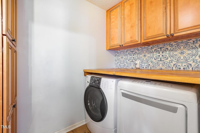 clothes washing area featuring cabinets, washing machine and dryer, and a textured ceiling