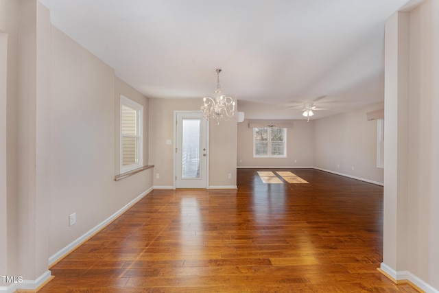 empty room with ceiling fan with notable chandelier and dark hardwood / wood-style flooring