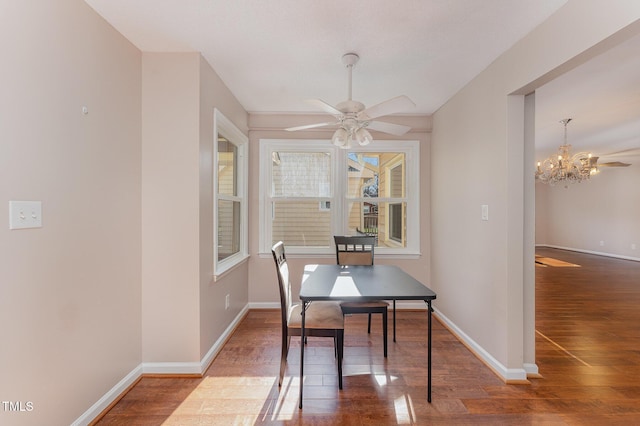 dining space featuring hardwood / wood-style flooring and ceiling fan with notable chandelier