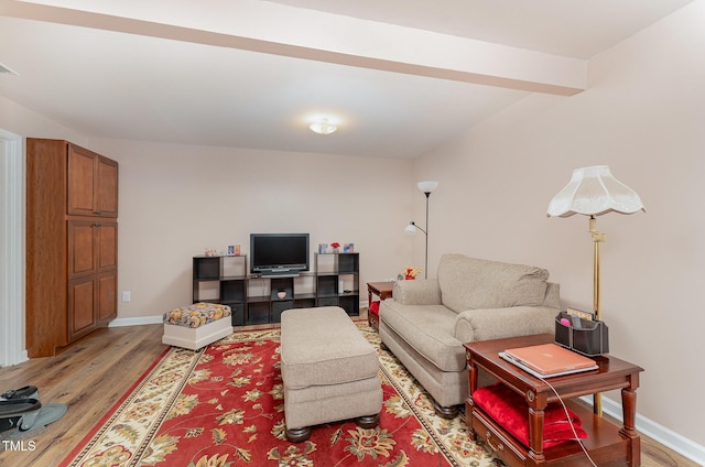 living room featuring beamed ceiling and light wood-type flooring