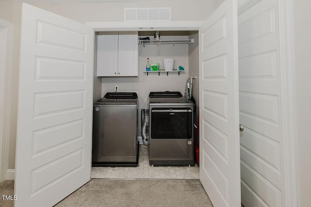 washroom with cabinets, washing machine and dryer, and light carpet