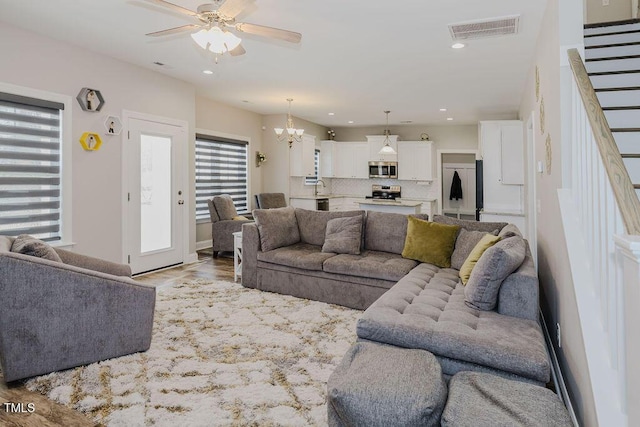 living room with sink, ceiling fan with notable chandelier, and light hardwood / wood-style flooring