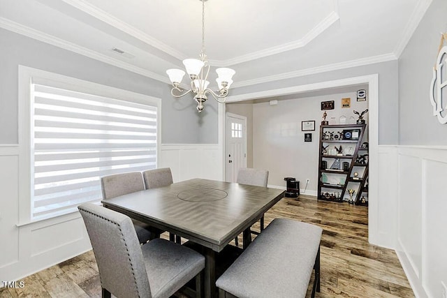 dining area featuring ornamental molding, a chandelier, and hardwood / wood-style floors