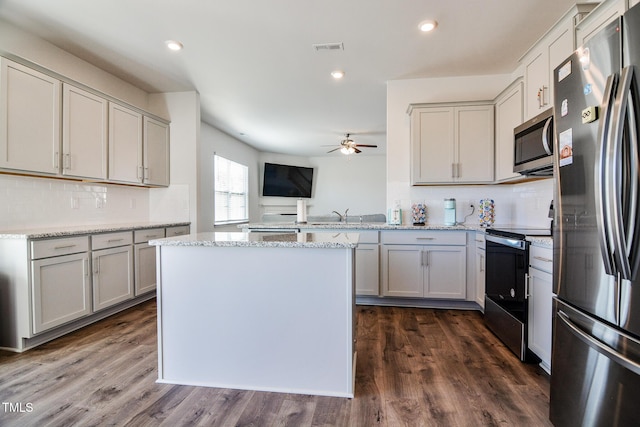 kitchen with light stone counters, dark hardwood / wood-style flooring, gray cabinetry, and appliances with stainless steel finishes