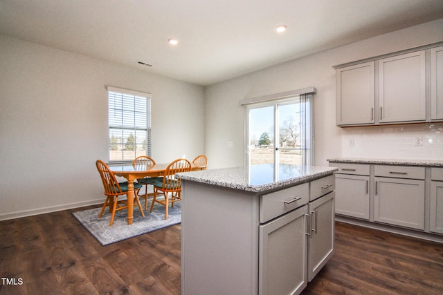 kitchen with light stone counters, dark hardwood / wood-style floors, and a center island