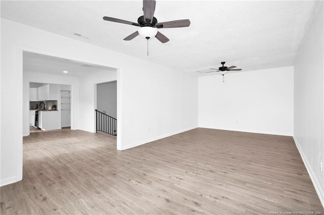 spare room with ceiling fan, light wood-type flooring, and built in shelves