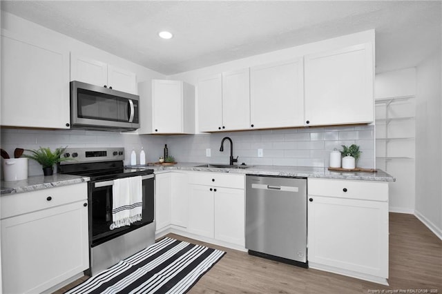 kitchen with white cabinets, sink, appliances with stainless steel finishes, and light hardwood / wood-style flooring