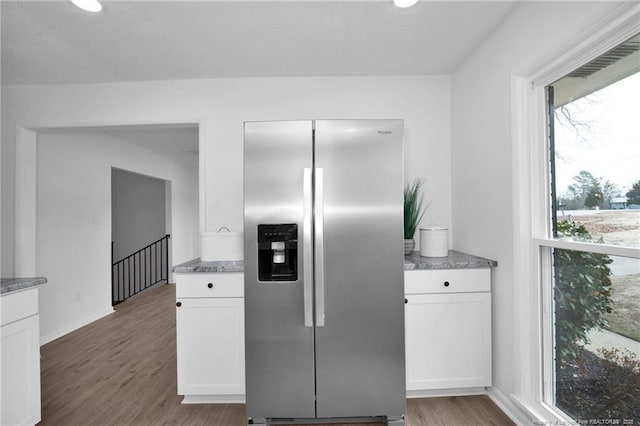 kitchen featuring stainless steel fridge with ice dispenser, hardwood / wood-style flooring, and white cabinetry